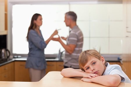 Sad little boy hearing his parents arguing