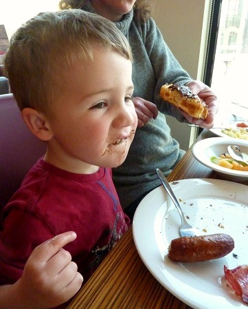 Henry Saunders eating chocolate covered croissant and sausage at Travelodge