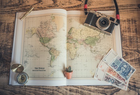 World map with travel accessories, compass, money, camera | photo Chris Lawton, Unsplash