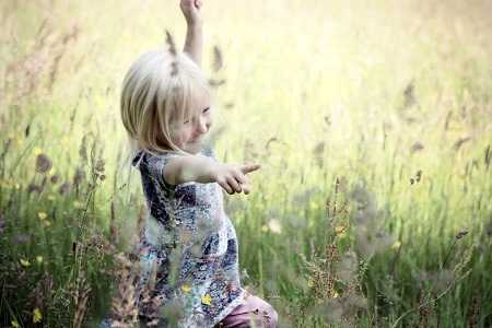 Girl having fun in the wildflowers and grass field of Cheshire