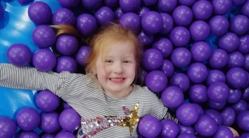 A girl is having fun in the sea of balls at Inflata Nation, Trafford