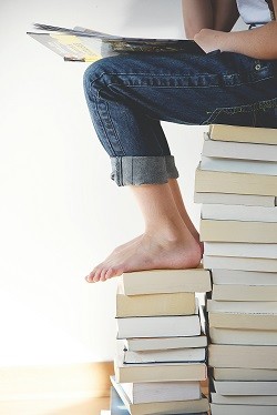 Student sitting on books by Gaelle Marcel from unsplash