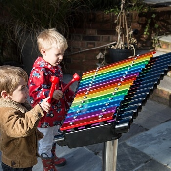 Toddlers playing on outdoor metallophone