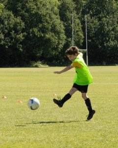 Young soccer player hits the ball | Photo by Theo Latham