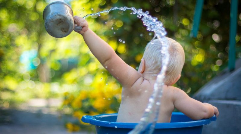 Baby splashing in a basin outside, in the hot weather | Photo by lubomirkin from unsplash
