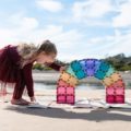 Girl playing with CONNETIX Pastel Magnetic Building Tiles on the beach.