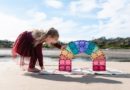 Girl playing with CONNETIX Pastel Magnetic Building Tiles on the beach.