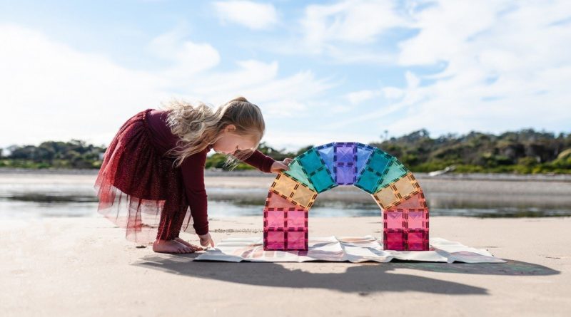 Girl playing with CONNETIX Pastel Magnetic Building Tiles on the beach.