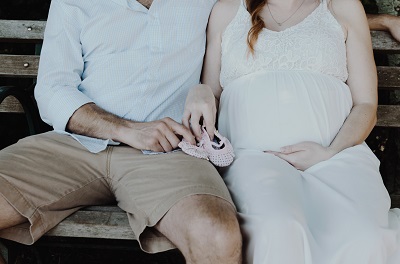 Pregnant woman and a man seating on a bench