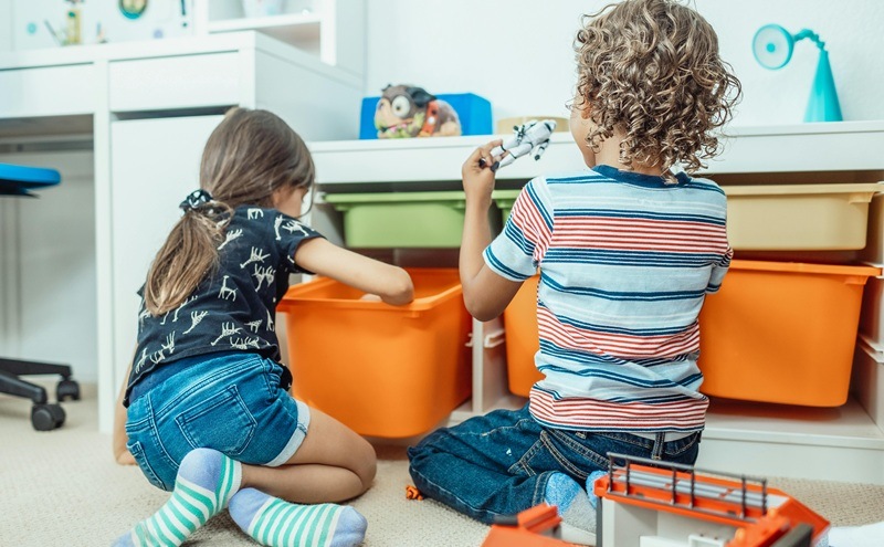 A boy and a girl are sorting out their toys