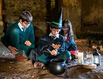 Kids in wizards and witch costumes brewing potion | Photo by kampus at pexels,