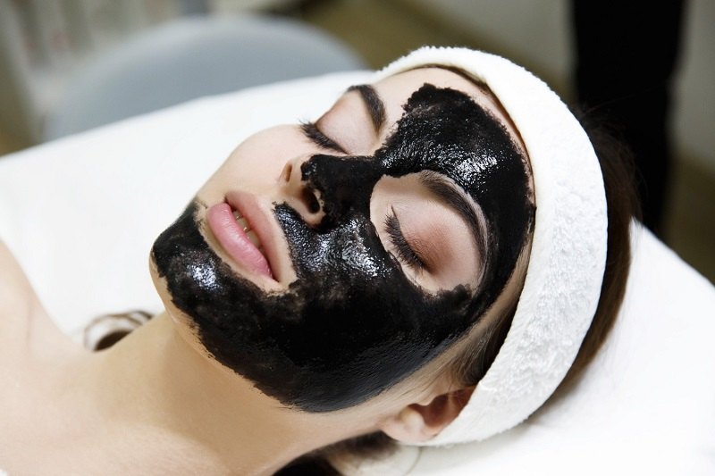 Woman having facial using activated charcoal mask