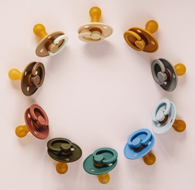 Multicolored baby pacifiers, arranged in a circle | Photo by Kristina Paukshtite, pexels