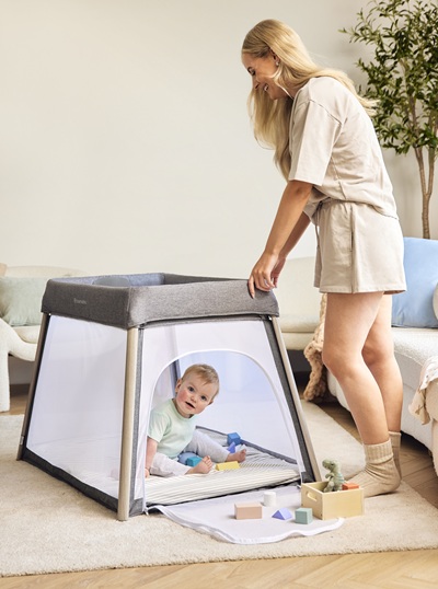 Baby in IBLI Scout playpen with mum standing nearby