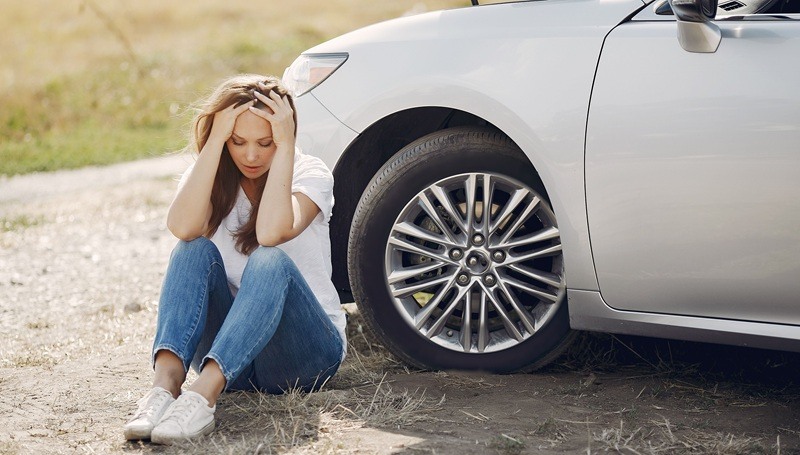 Woman sitting next to her car