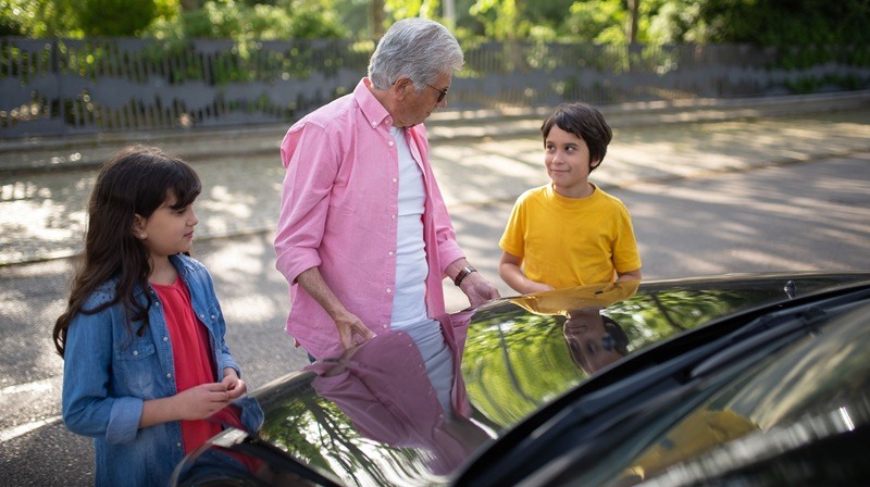 A man with kids next to the car
