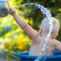 Baby splashing in a basin outside, in the hot weather | Photo by lubomirkin from unsplash
