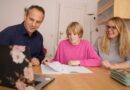 A girl with her parents in front of the computer