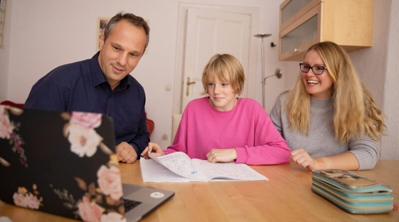 A girl with her parents in front of the computer